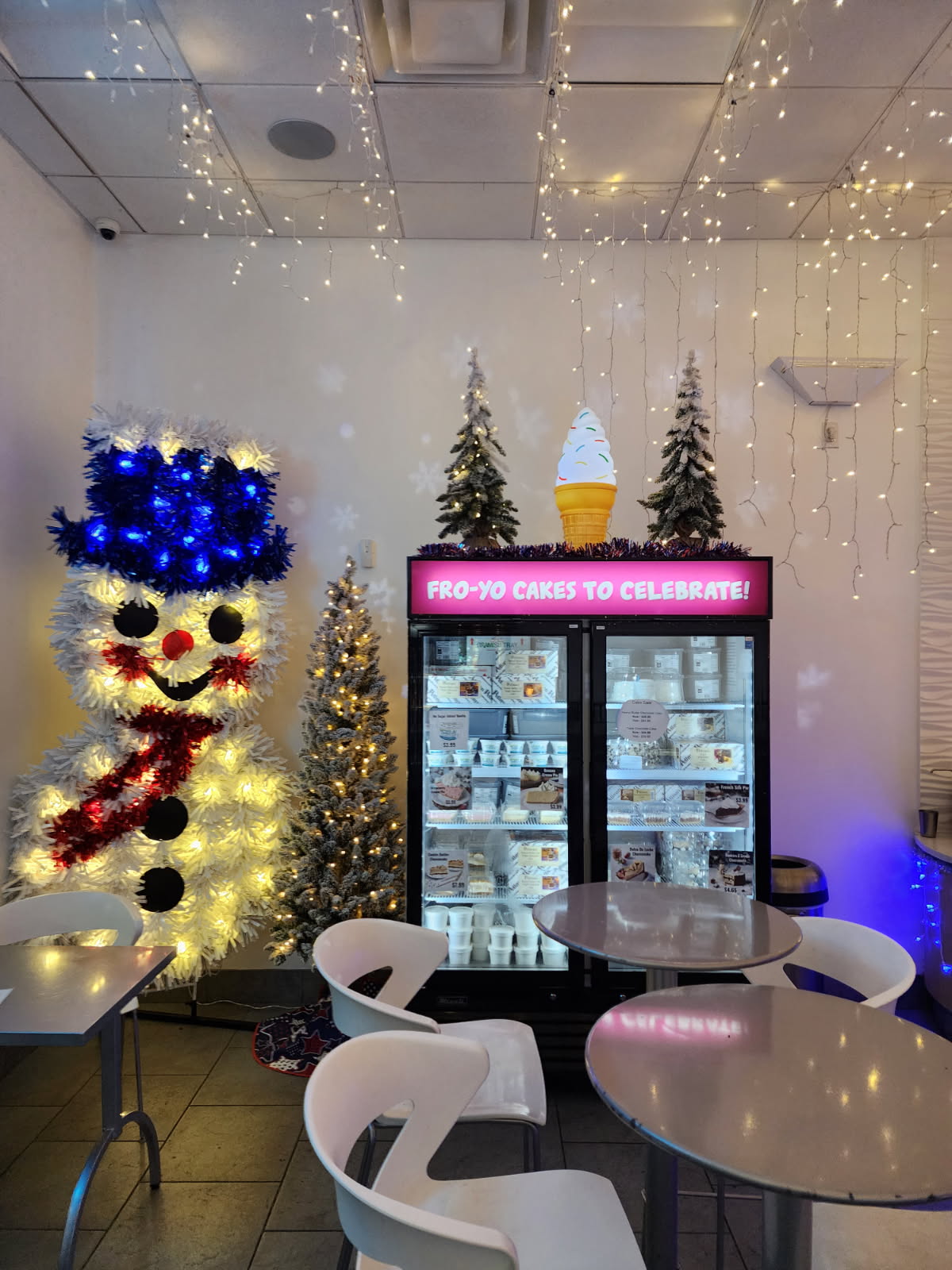 Frosty Froyo interior featuring illuminated snowman decoration, Christmas trees, and frozen cake display case in Champions Gate